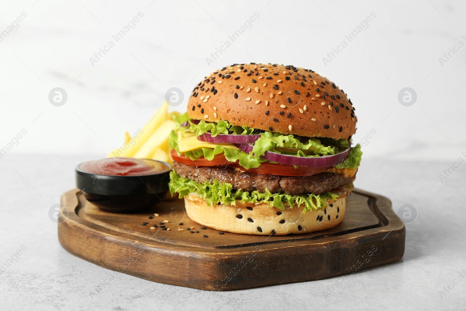 Burger with delicious patty, french fries and sauce on light table Photo of Burger with delicious patty, french fries and sauce on light table