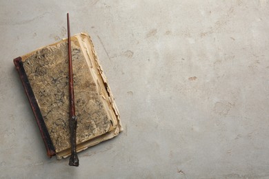 Photo of Magic wand and old book on light textured background, top view. Space for text