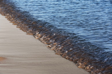 Photo of View of sea water and beach sand on sunny summer day