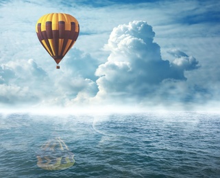 Image of Dream world. Hot air balloon in cloudy sky over misty sea