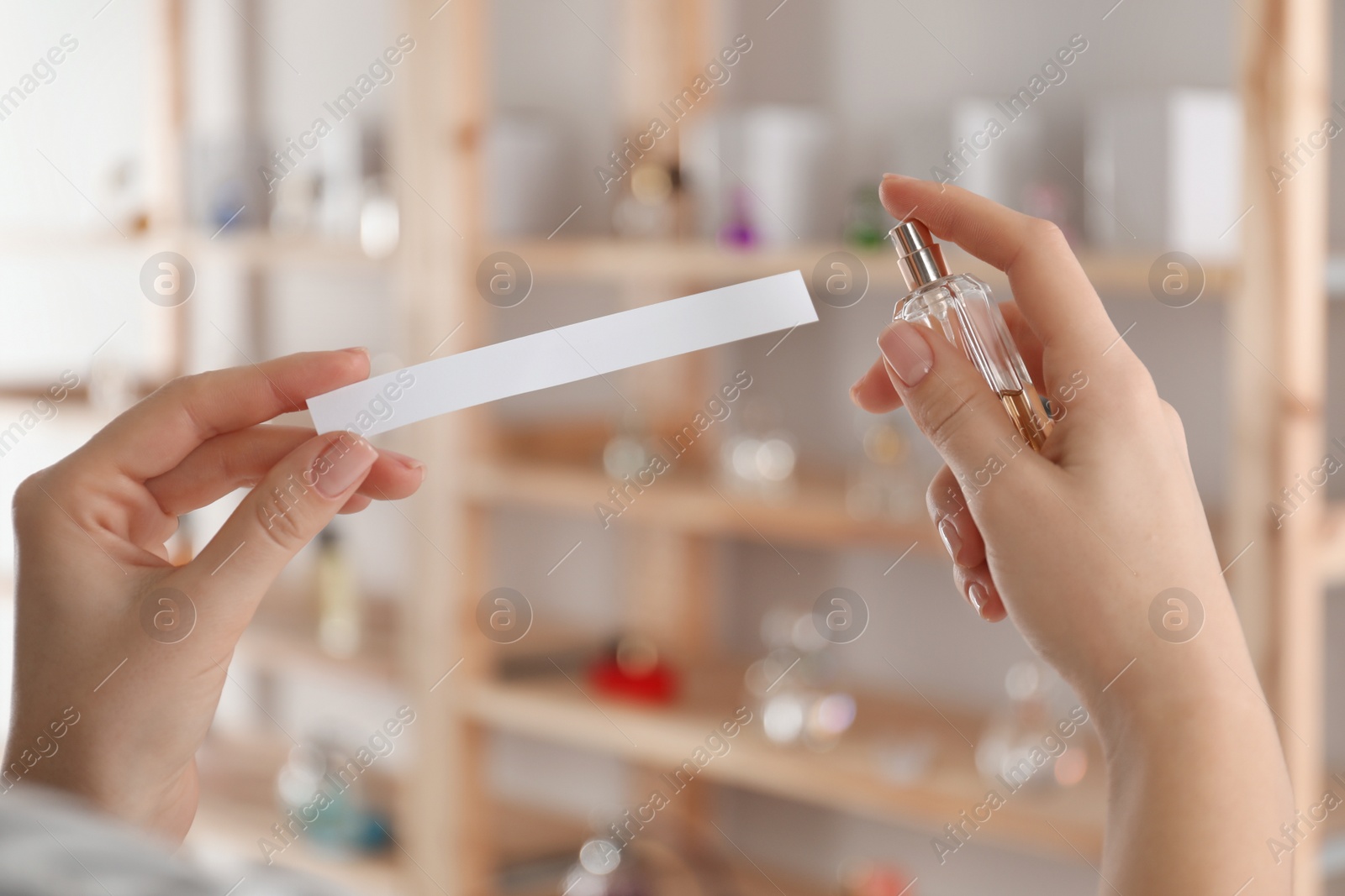 Photo of Woman with bottle of perfume and blotter indoors, closeup