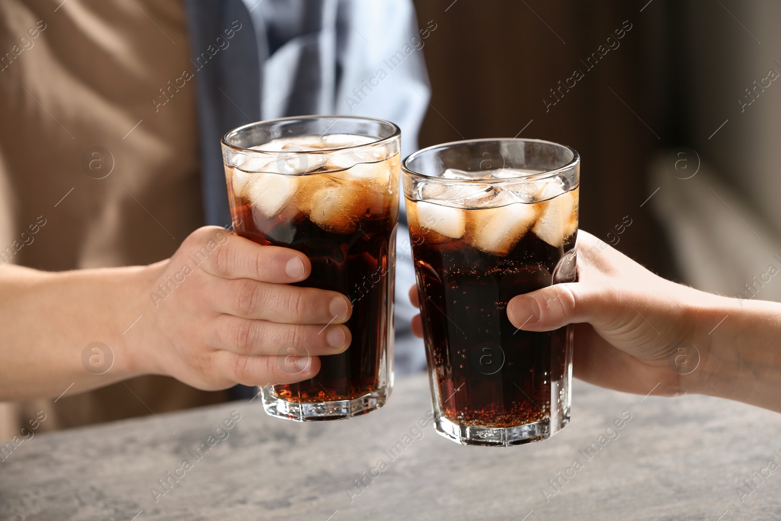 Photo of Couple with glasses of cold cola at table indoors, closeup