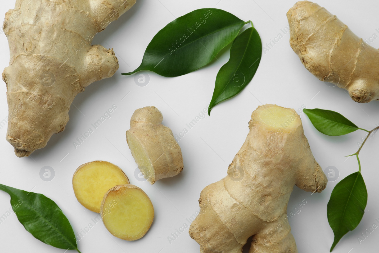 Photo of Fresh ginger with green leaves on white background, flat lay