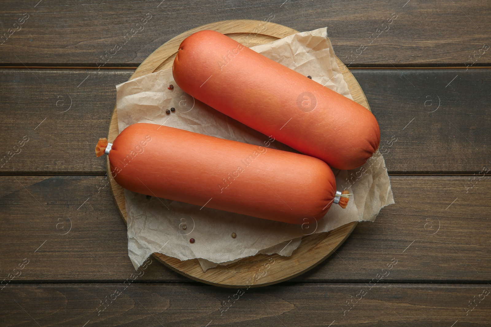 Photo of Board with tasty boiled sausages on wooden table, top view