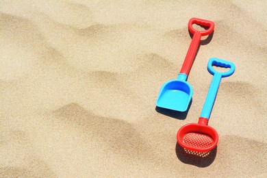 Photo of Plastic shovel and sieve on sand, space for text. Beach toys