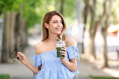 Young woman with plastic cup of healthy smoothie outdoors