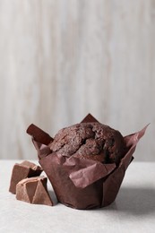 Photo of Tasty chocolate muffin on grey table, closeup. Space for text