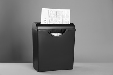 Photo of Paper shredder with newspaper on color background