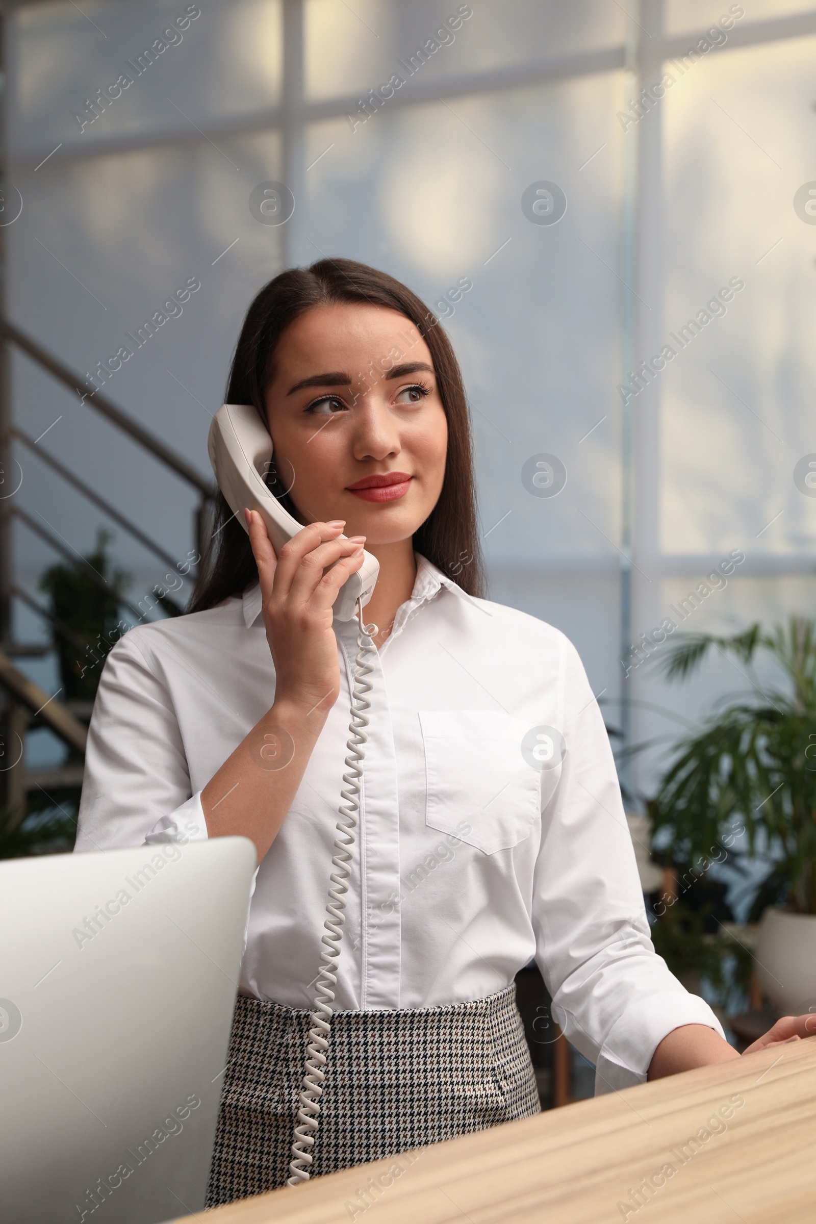 Photo of Female receptionist talking on phone at workplace