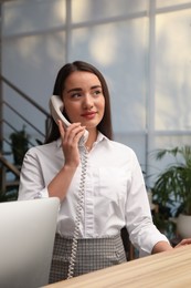 Female receptionist talking on phone at workplace