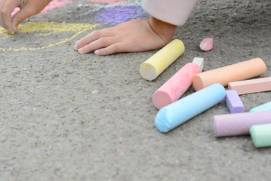 Little child drawing butterfly and hearts with chalk on asphalt, closeup
