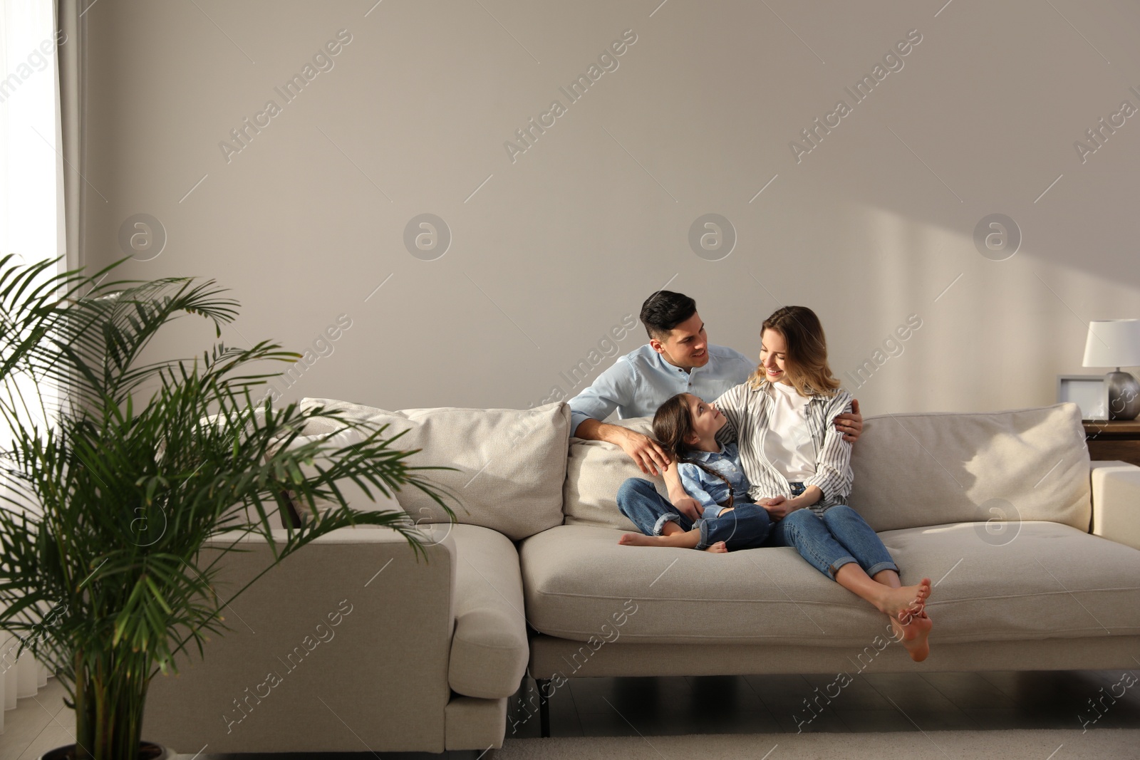 Photo of Family with little daughter resting on sofa in living room