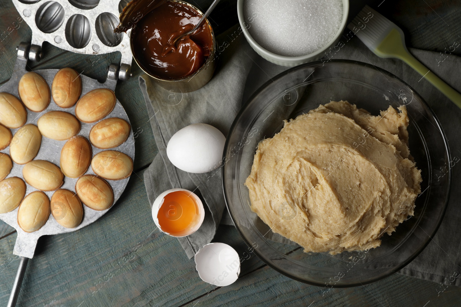 Photo of Freshly baked homemade walnut shaped cookies, dough and ingredients on wooden table, flat lay