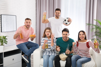 Group of friends watching football at home