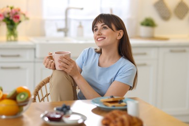 Photo of Smiling woman drinking coffee at breakfast indoors