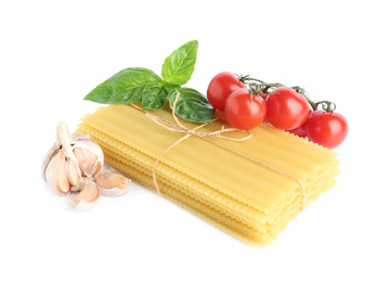 Photo of Uncooked lasagna sheets with cherry tomatoes, garlic and basil isolated on white