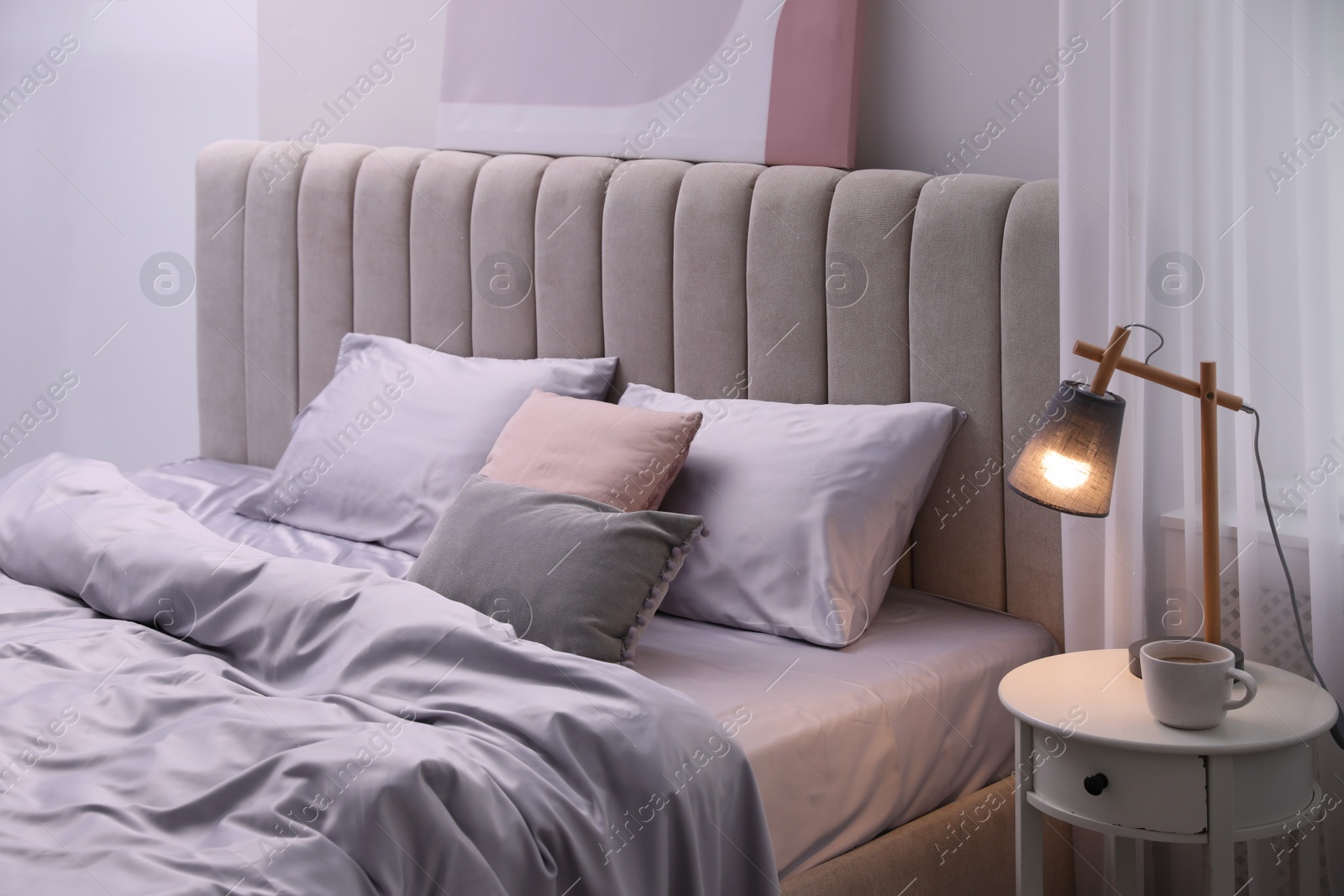 Photo of Cozy bed with soft silky bedclothes in light room