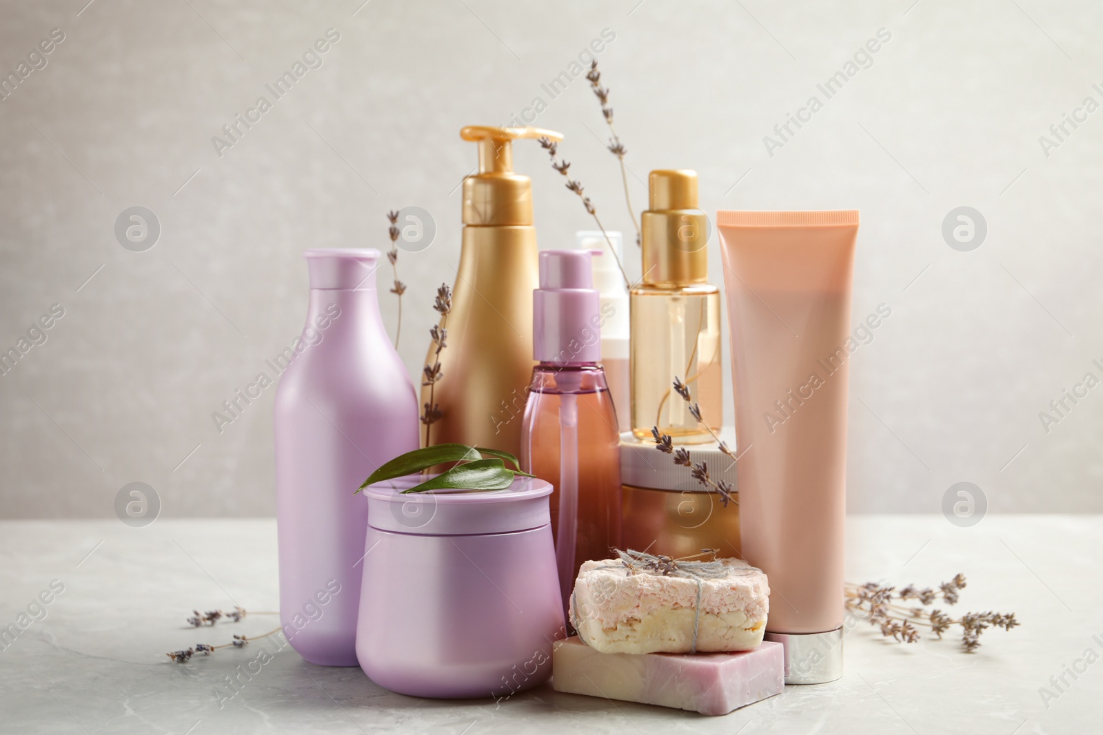 Photo of Set of hair cosmetic products and flowers on grey table