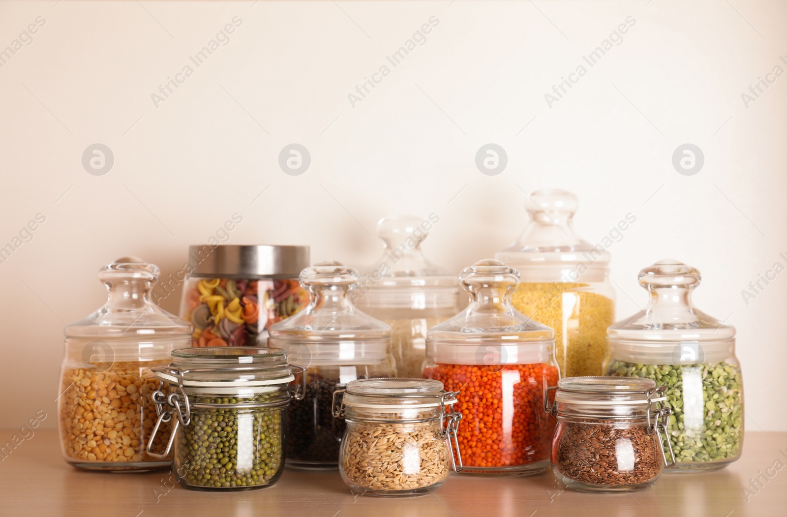 Photo of Glass jars with different types of groats on wooden shelf