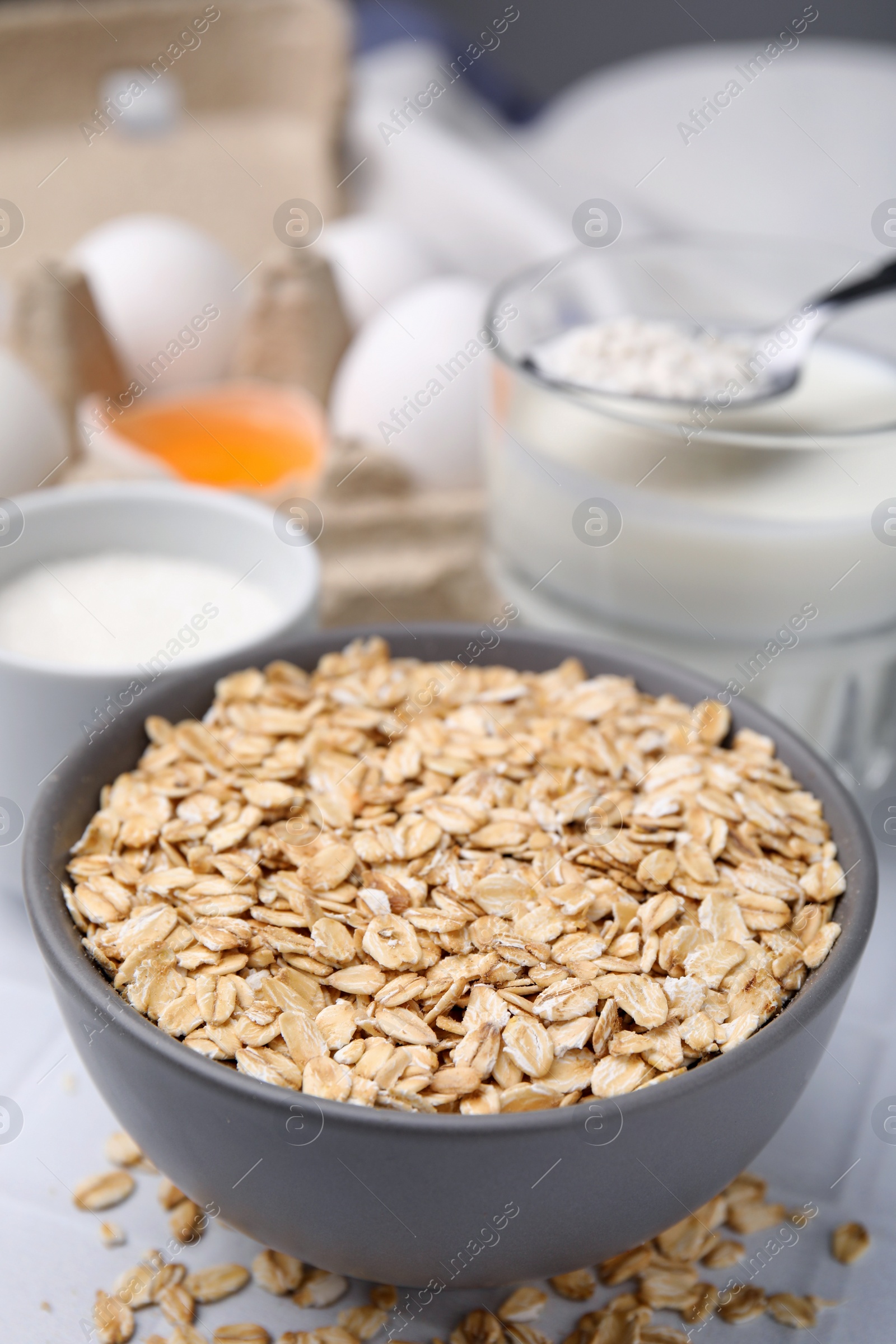 Photo of Different ingredients for cooking tasty oatmeal pancakes on white table, closeup