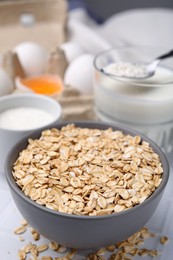 Photo of Different ingredients for cooking tasty oatmeal pancakes on white table, closeup