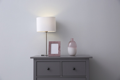 Modern grey chest of drawers near light wall in room. Interior design