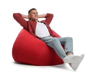 Photo of Handsome man resting on red bean bag chair against white background