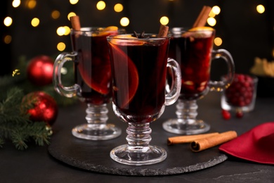 Aromatic mulled wine on black table against blurred festive lights