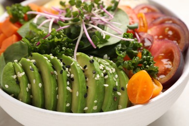 Photo of Delicious vegan bowl with avocados, microgreens and tomatoes on grey table, closeup