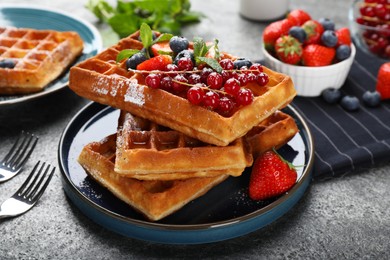 Photo of Delicious Belgian waffles with berries served on grey table