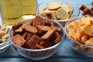 Different crispy rusks in bowls on light blue wooden table