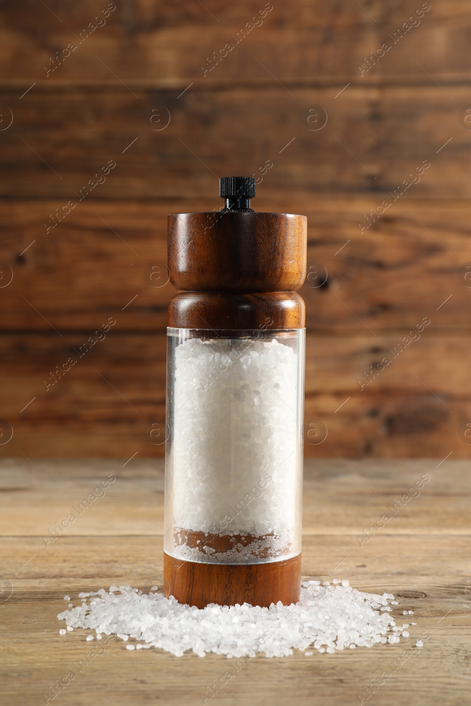 Photo of Shaker with salt on wooden table, closeup