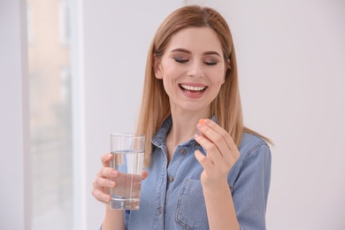 Photo of Young woman taking vitamin indoors