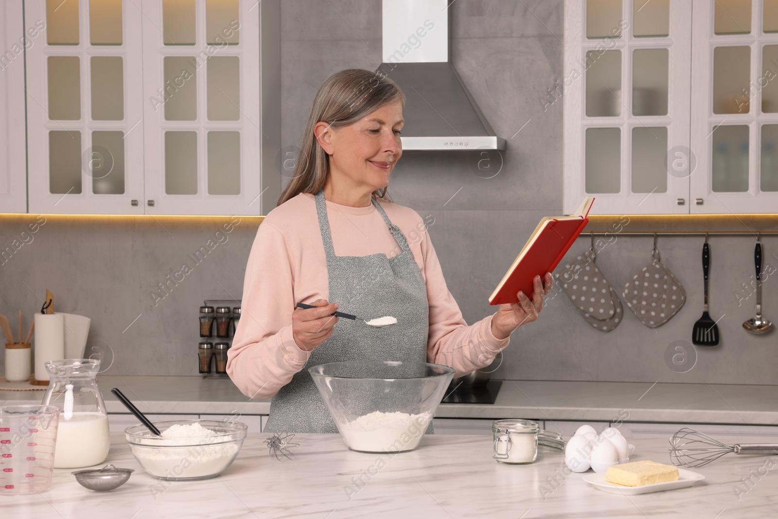 Photo of Senior woman with recipe book cooking in kitchen