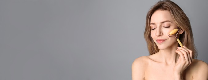 Image of Young woman using natural jade face roller on light grey background, space for text. Banner design
