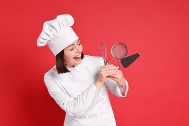Photo of Happy confectioner holding professional tools on red background