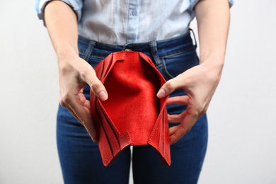 Photo of Woman showing empty wallet on light background, closeup