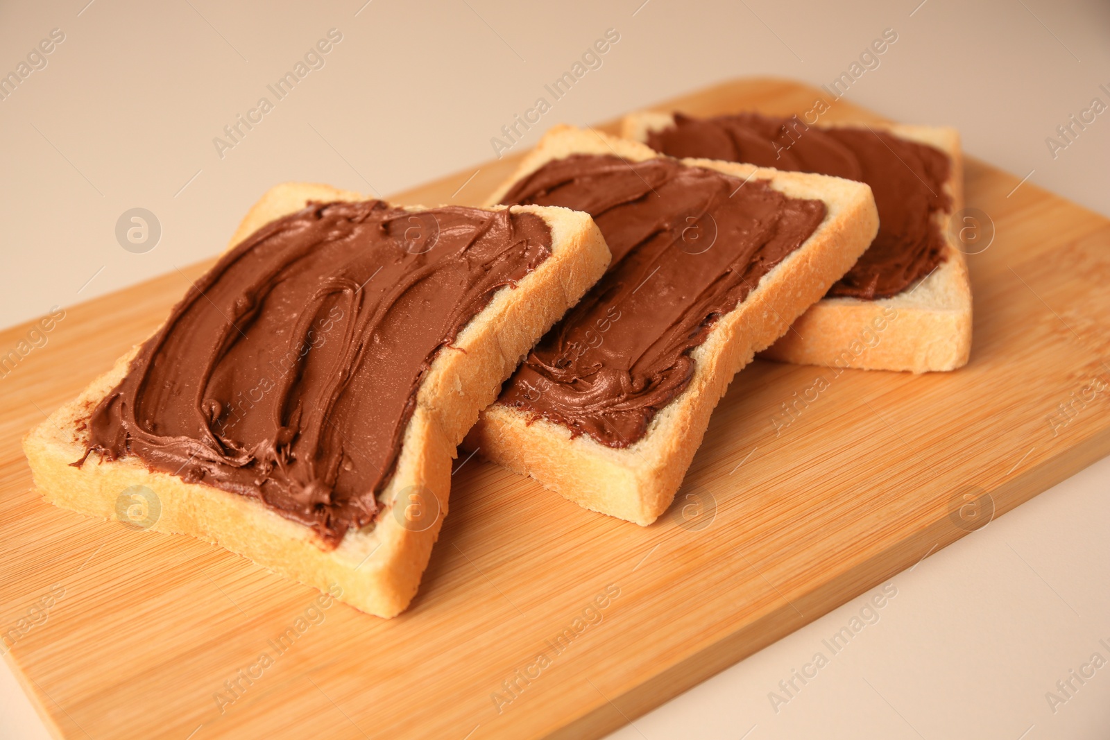 Photo of Tasty toasts with chocolate paste on beige background, closeup