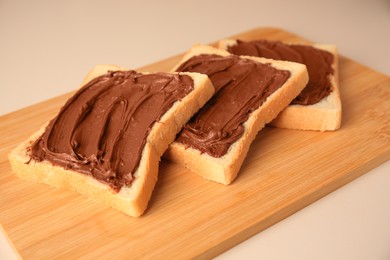 Photo of Tasty toasts with chocolate paste on beige background, closeup