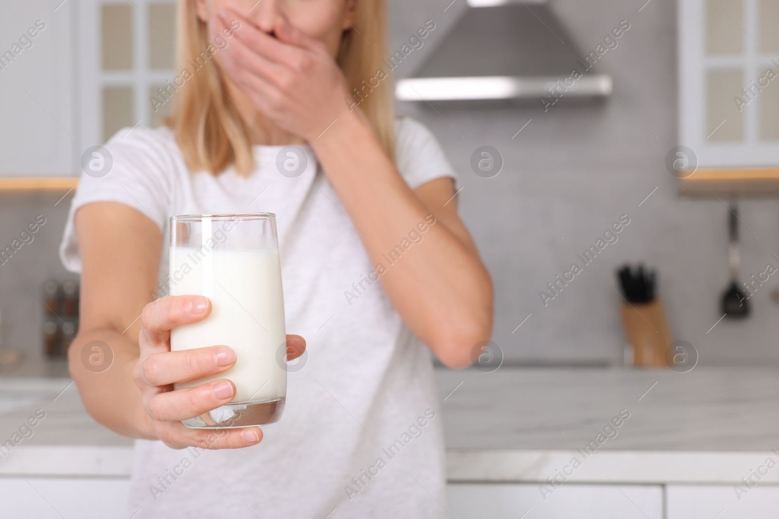 Photo of Woman with glass of milk suffering from lactose intolerance in kitchen, closeup. Space for text