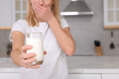 Woman with glass of milk suffering from lactose intolerance in kitchen, closeup. Space for text