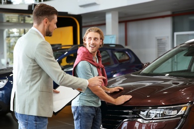 Salesman with customer in modern car dealership