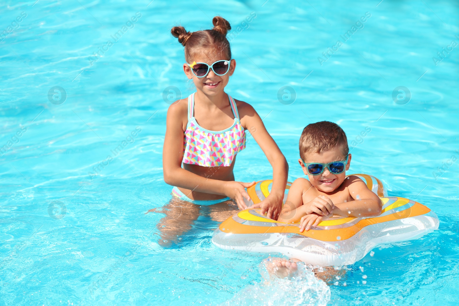 Photo of Cute little children with inflatable ring in swimming pool
