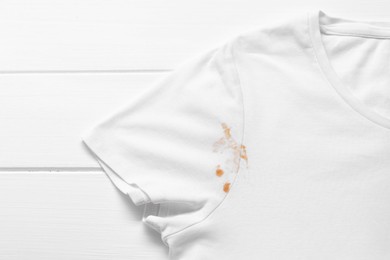 Photo of Stylish t-shirt with stain on white wooden table, top view
