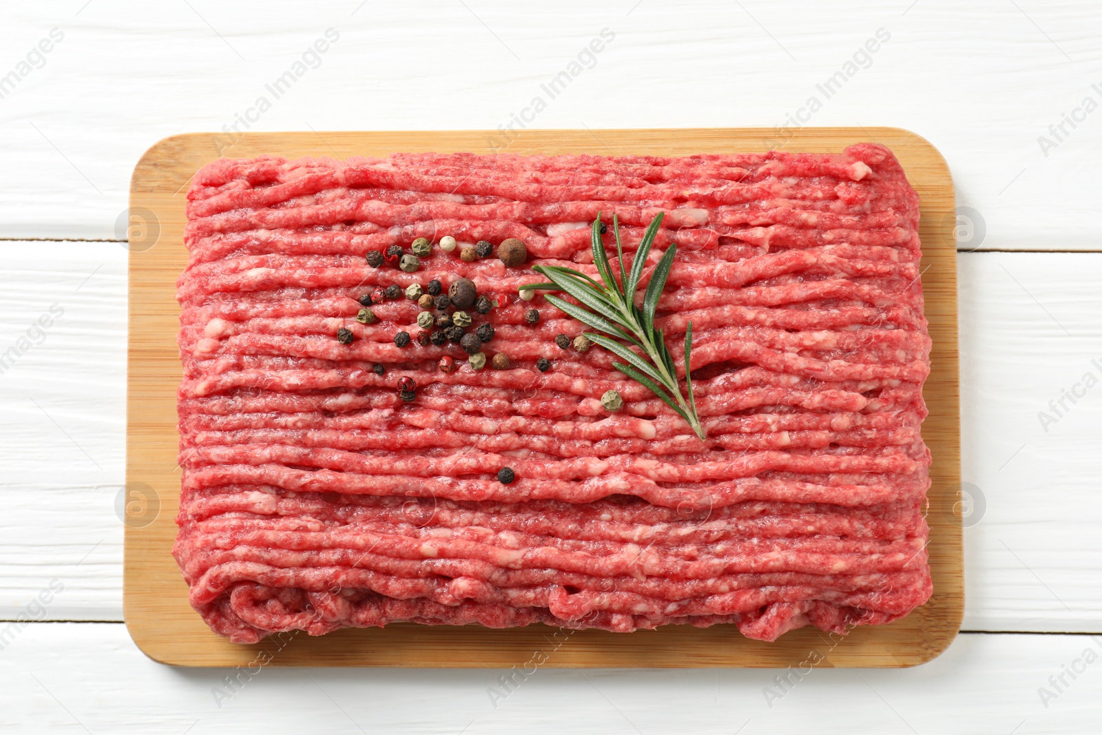 Photo of Raw ground meat, rosemary and peppercorns on white wooden table, top view