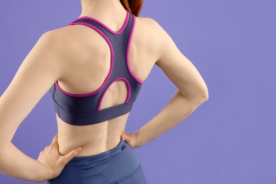 Photo of Woman wearing sportswear on violet background, back view. Space for text