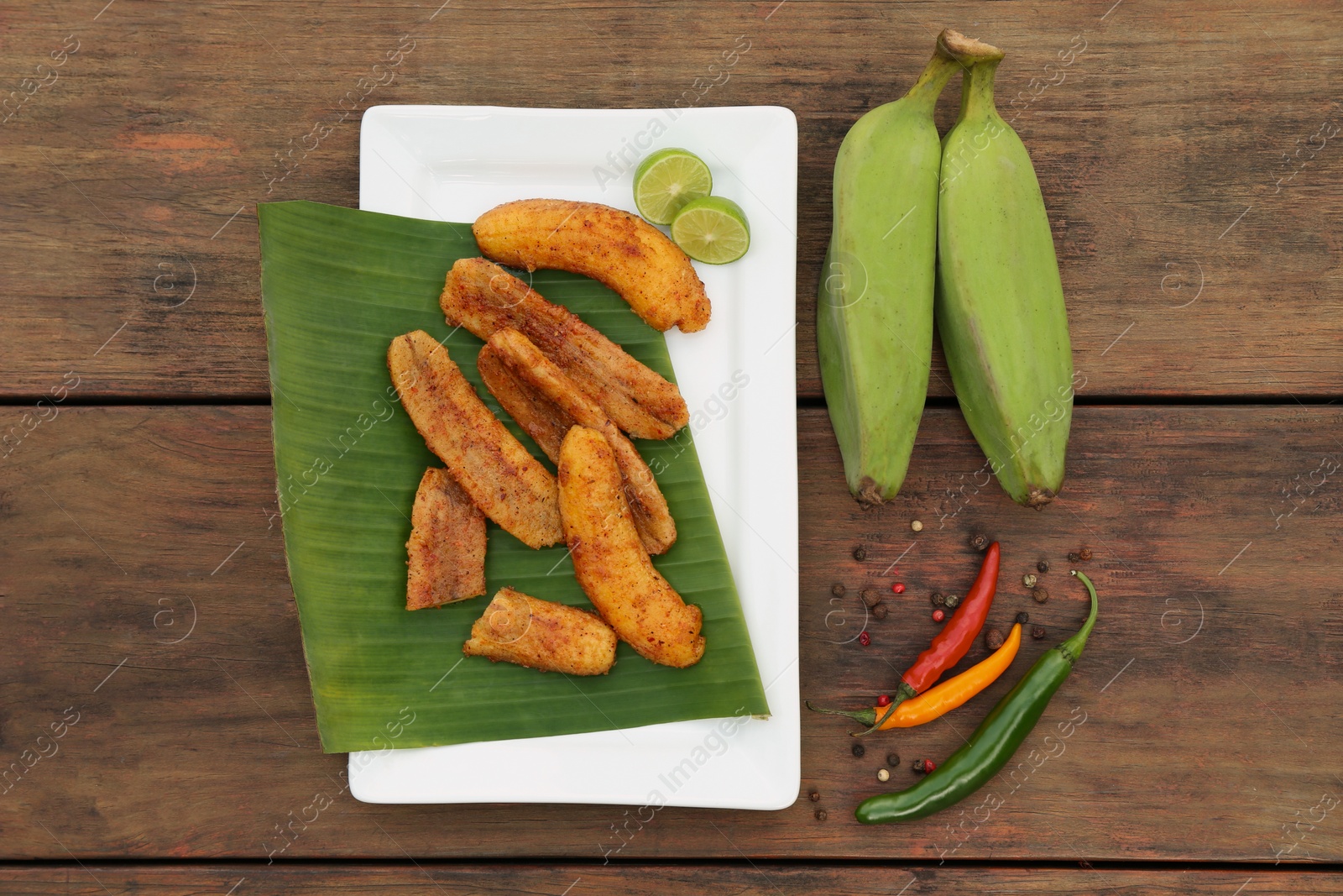 Photo of Delicious fried bananas, fresh fruits and different peppers on wooden table, flat lay