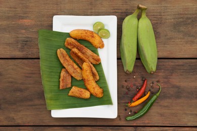 Photo of Delicious fried bananas, fresh fruits and different peppers on wooden table, flat lay