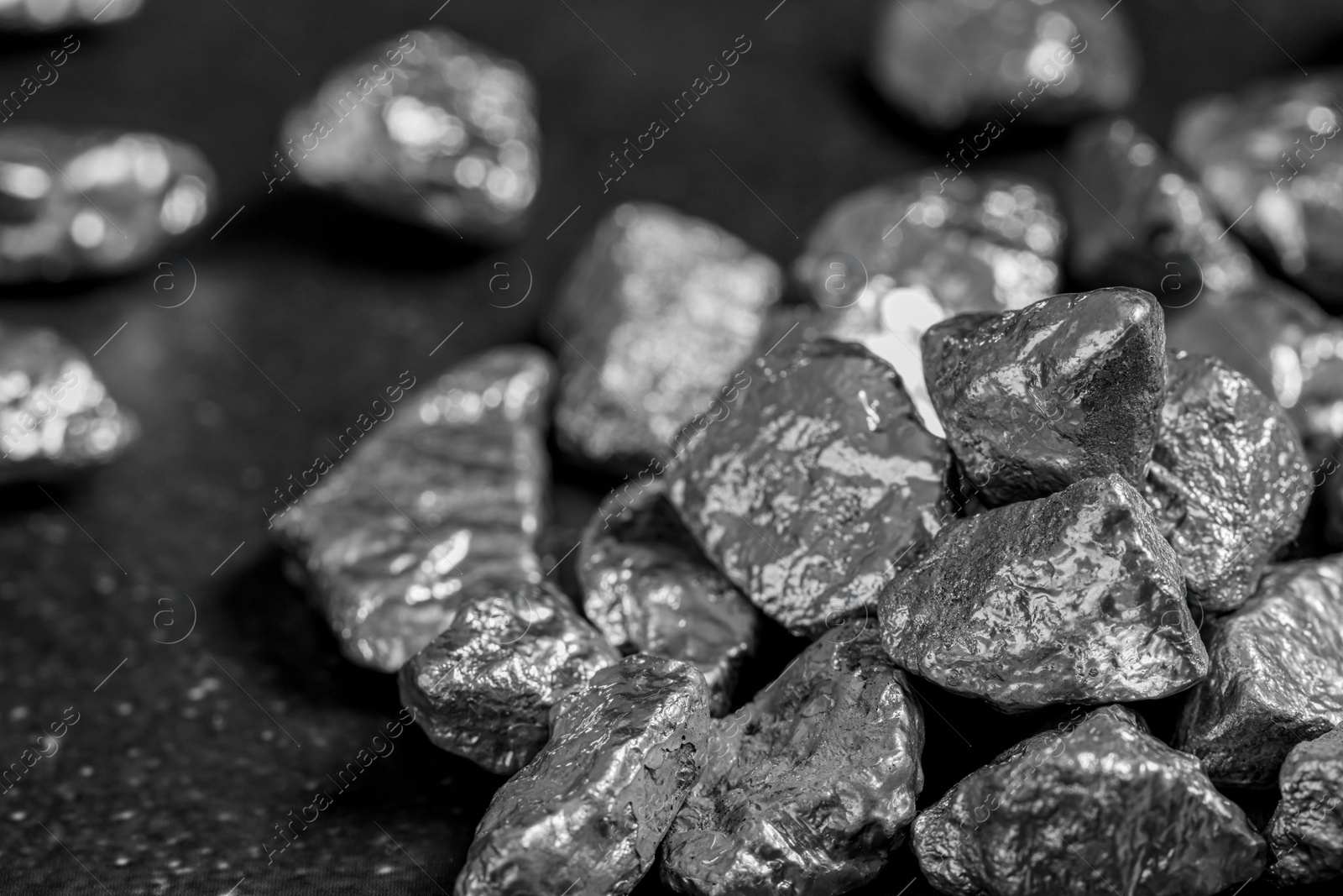 Photo of Pile of silver nuggets on black table, closeup