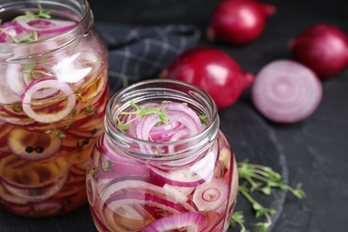 Photo of Jars of pickled onions on grey table, closeup